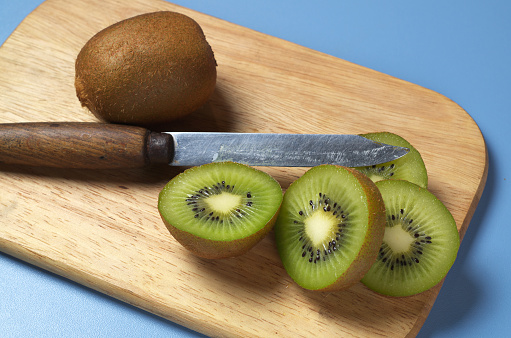 Ripe kiwi fruits and slice on wooden kitchen board
