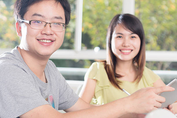 istock portrait of asian students discussing with tablet in classroom 521436091
