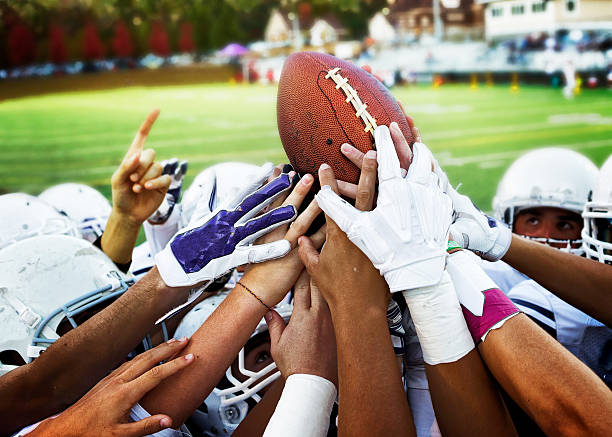 American Football Football players holding up football. huddle stock pictures, royalty-free photos & images