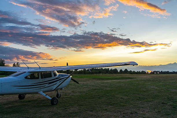 Small private airplane parked on a local runway at sunset. The sky is yellow and blue with backlit clouds in orange colour, Hel, Poland, Europe.