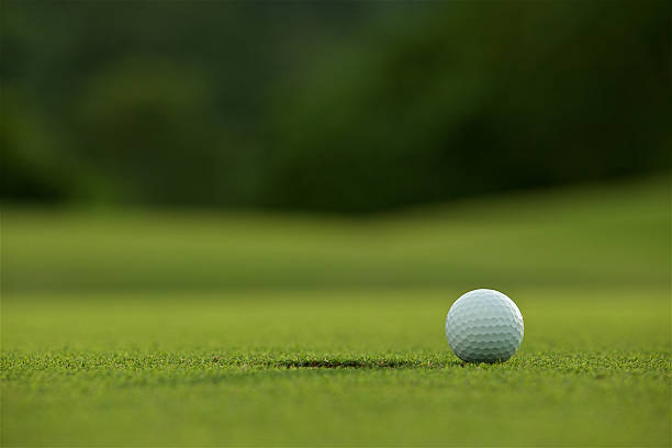 istock white golf ball on fairway with green background 521463868