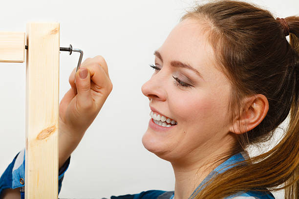 Woman assembling wooden furniture using screwdriver.