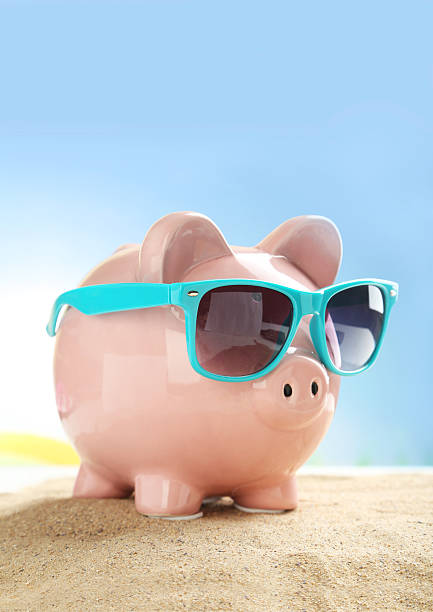 istock Piggy bank with sunglasses on the beach 521469200