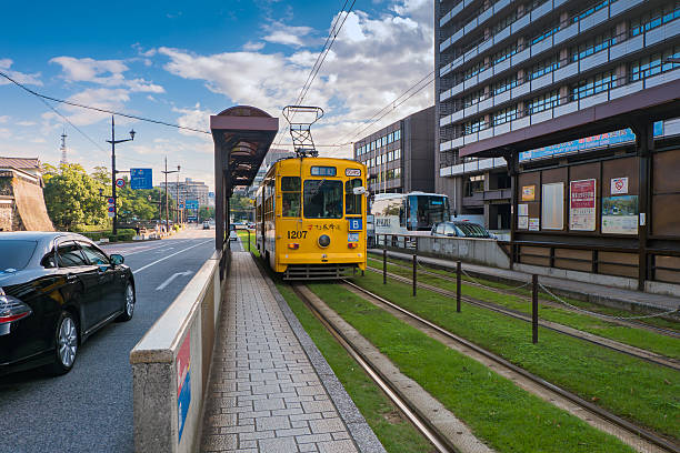 Fukuoka, Japan - September 27, 2014: Classic tram of Kumamoto city at the tram stop near Kumamoto castle in Kumamoto, Kyushu , Japan. Team is the easiest way to access tourist spot in Kumamoto city is by using local trams service.