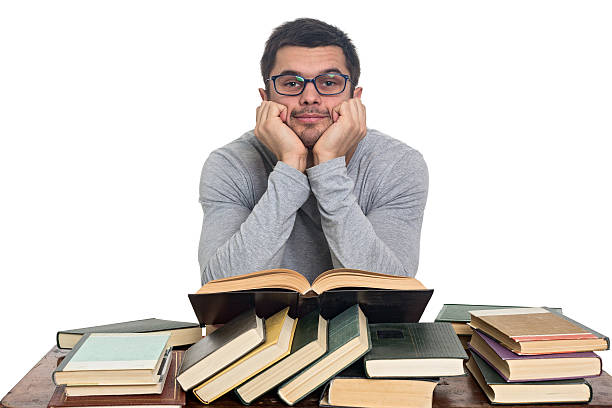istock Young man in glasses reads book at table 521472490