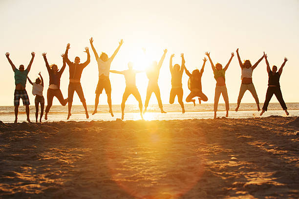 Young people jumping at the beach of St.Peter-Ording in Germany Twelve young people jumping at the beach of St.Peter-Ording in Germany in the fantastic sunset. jumping teenager fun group of people stock pictures, royalty-free photos & images