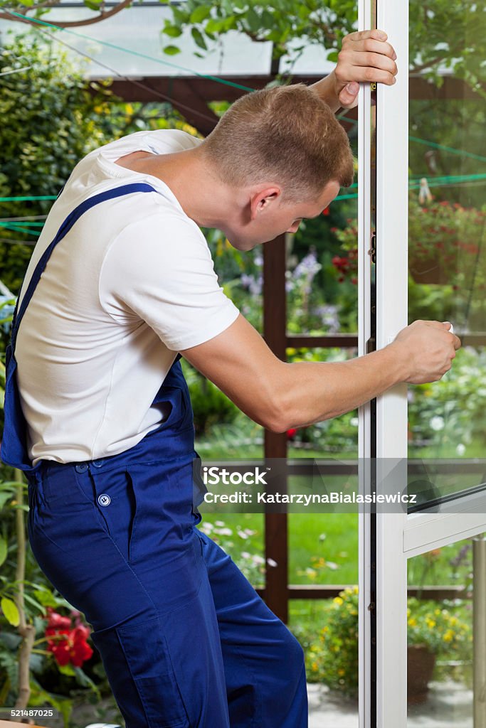 Repairman adjusting a window handle Young man adjusting a terrace door handle Adjusting Stock Photo
