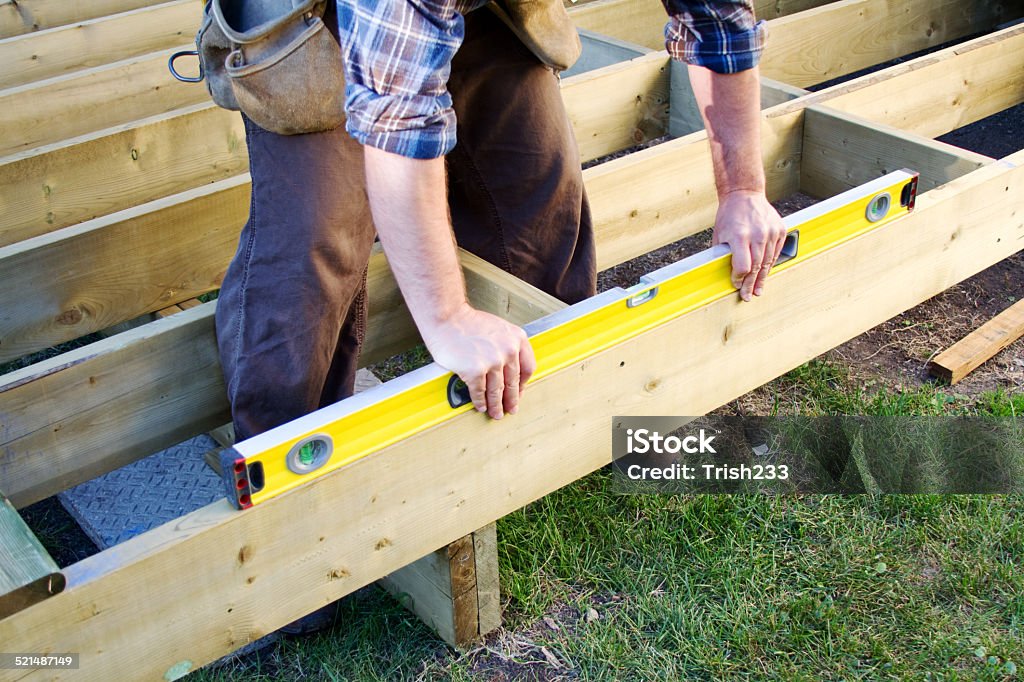 Is it level? Carpenter checking level of deck boards Deck Stock Photo