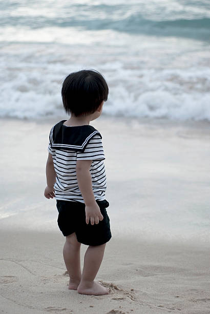 Little boy in sailor's uniform on beach stock photo