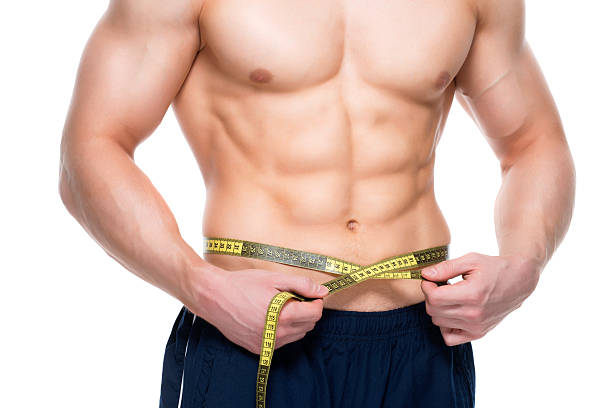 istock Man with a muscular torso uses measuring tape 521496690
