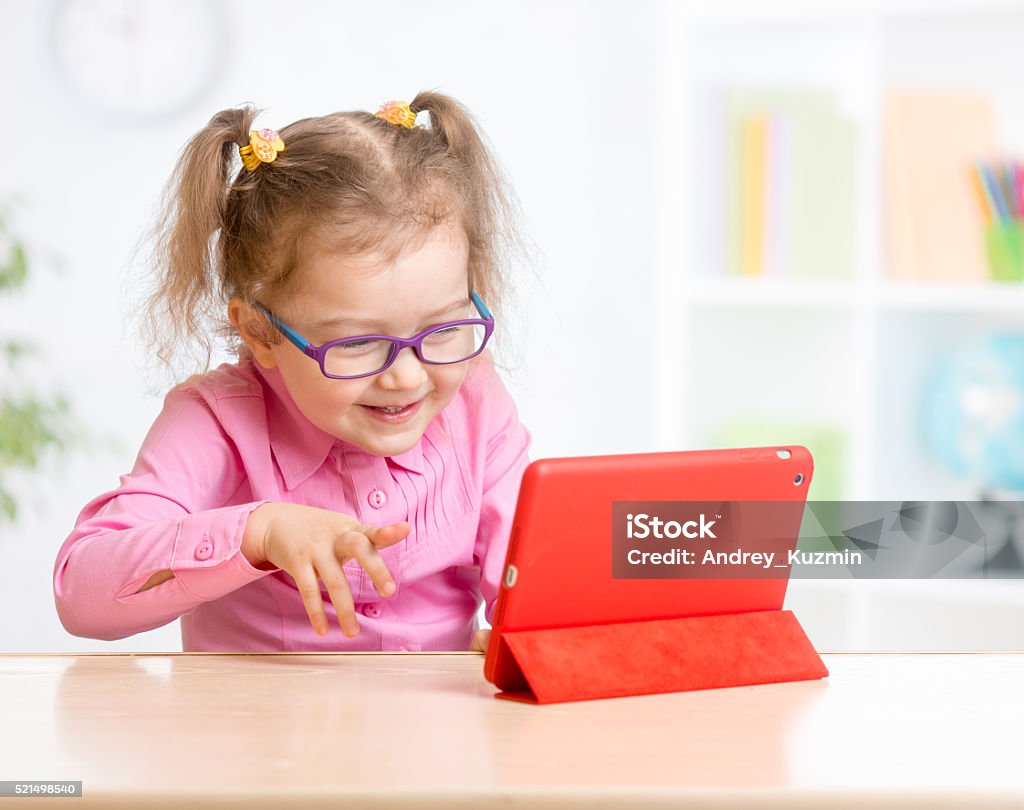 Kid with tablet PC in glasses learning Kid with tablet PC in glasses learning with great interest Digital Tablet Stock Photo