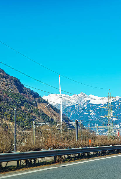 дорога с видом на линиях передачи электроэнергии и ветряные мельницы - single line outdoors vertical switzerland стоковые фото и изображения
