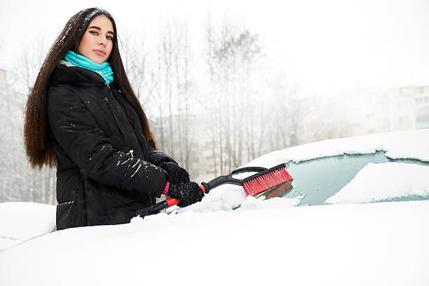 istock Beautiful young woman removing snow from her car 521504992