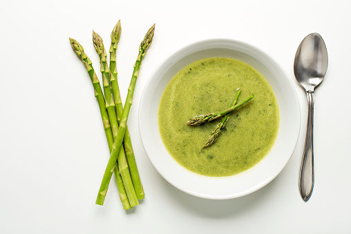 Fresh asparagus soup on white background overhead shoot