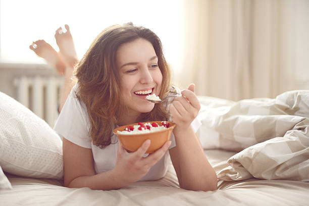 girl in bedroom girl in bedroom eating cottage cheese with raspberries cottage cheese photos stock pictures, royalty-free photos & images