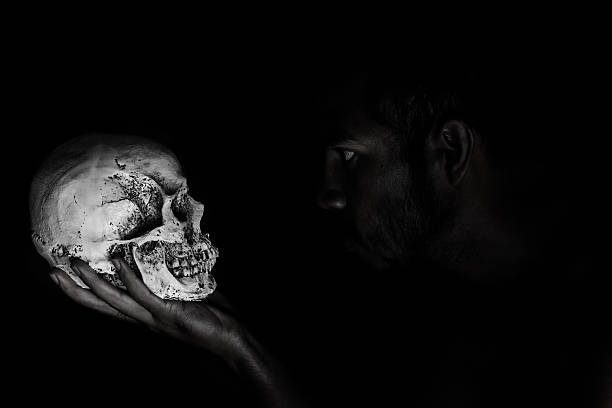 istock Man in shadow stare human skull that hold in hand 521515927