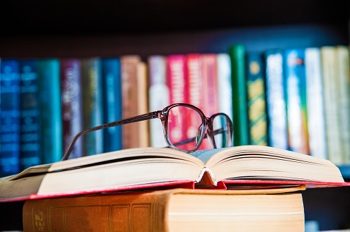 glasses and book on background bookcase close up