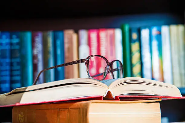 Photo of glasses and book on background bookcase