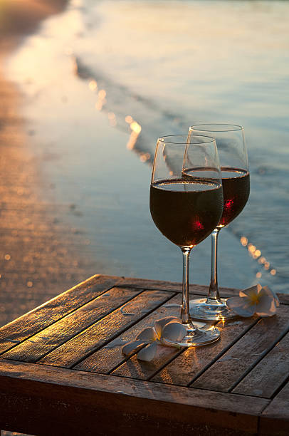 istock Romantic beach scene: two glasses of red wine at sunset 521528116