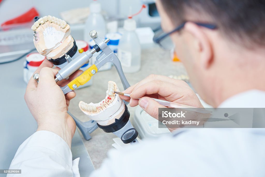 dental prosthesis work Dental technician painting tooth during work on dentures at prosthesis laboratory Dentures Stock Photo