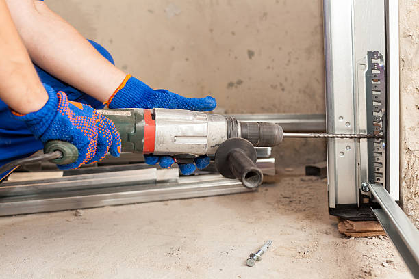 garage türen installation. arbeiter drills ein loch für den bolzen - scharnier stock-fotos und bilder