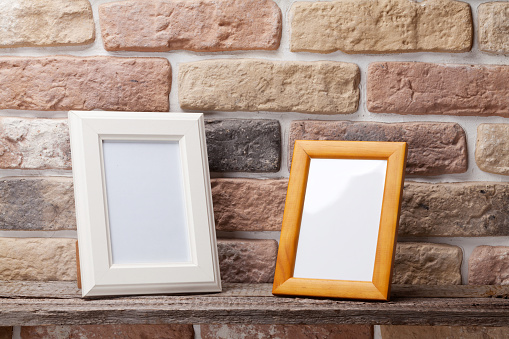 Blank photo frames on shelf in front of brick wall