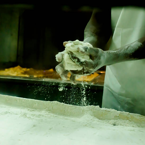 Making beignets in New Orleans Behind Cafe du Monde are the people making the delicious beignets.  This image taken through the observation window. beignet stock pictures, royalty-free photos & images