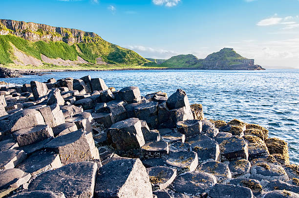 Giants Causeway and cliffs in Northern Ireland Giants Causeway, unique geological hexagonal formation of volcanic basalt rocks and cliffs in Antrim County, Northern Ireland, in sunset light giants causeway photos stock pictures, royalty-free photos & images