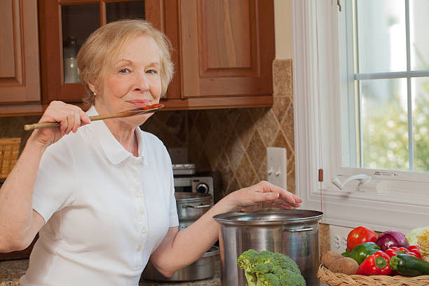 Home cooking: a senior woman tasting her suace stock photo