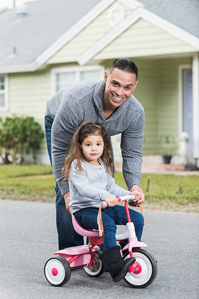 istock Hispanic father helping daughter ride tricycle 521545694