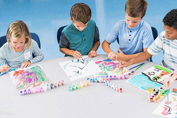istock Elementary school children in art class painting 521546202