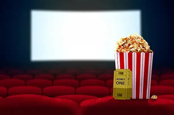 Photo of Cinema seat and pop corn facing empty movie screen