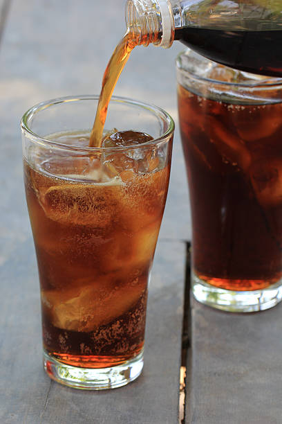 istock Pouring of cola with ice cubes on wood table. 521604436