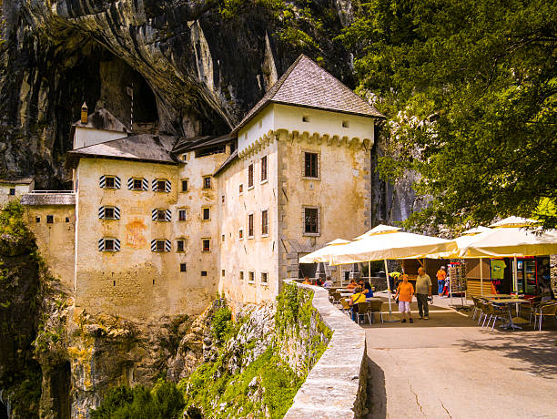 Postojna, Slovenia - July 11, 2014: View of the Predjama Castle, a renaissance castle partly built within a cave mouth and now serves as a famous tourist destination in Postojna, Slovenia. People can be seen in the foreground.