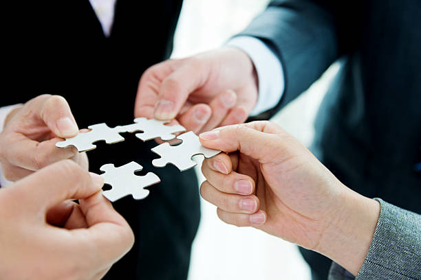 istock Four business people holding puzzle pieces 521605988