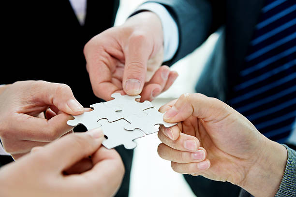 istock Four business people holding puzzle pieces 521606064