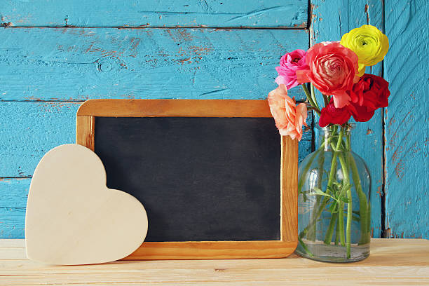 istock flowers next to empty blackboard, on wooden table. copy space 521607602
