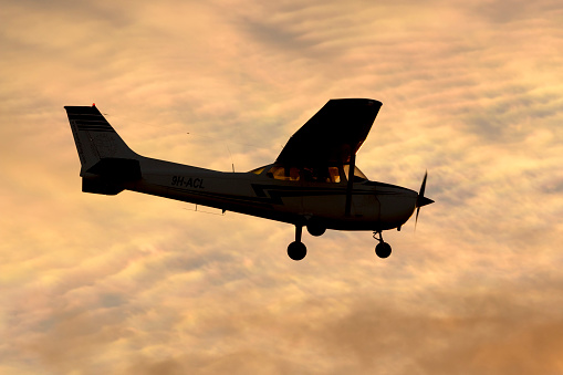 Luqa, Malta - December 6, 2014: Malta School of Flying Cessna 172M Skyhawk overflying runway 31 in the sunset.