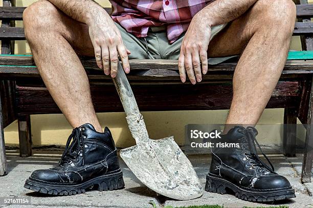 Mason With Hairy Legs In Boots Resting On A Bench Stock Photo - Download Image Now - Construction Worker, Men, Shovel