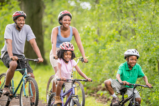 A family is going on a bike ride through the woods while on summer vacation.