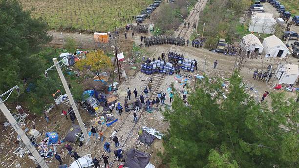 Clashes at the Greek-Macedonian border Idomeni, Greece - November 28, 2015: Macedonian riot police shelter behind their shields from stones hurled by refugees and migrants during clashes at the Greek-Macedonian border. Drone photo. riot tear gas stock pictures, royalty-free photos & images