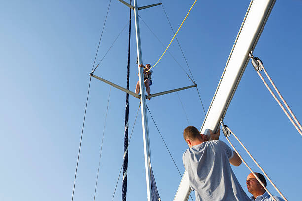 Sailors climbing the rope ladders of an old, historic sailing ship. Dutch flag visible