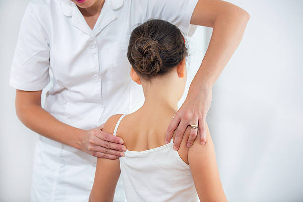 istock Chiropractic Doctor Adjusts Elementary Girl 521618309
