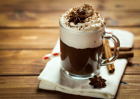 Hot Chocolate with whipped cream,cinnamon and star anise served on a wooden table