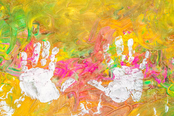 Child drawing painting with his white hands on colorful background