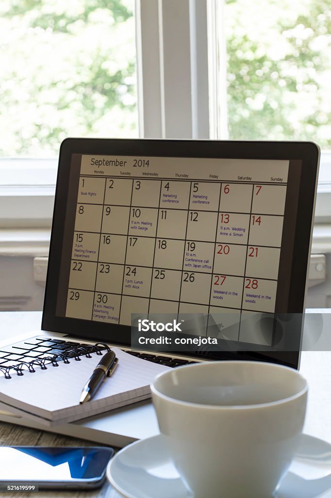 Checking monthly activities in the calendar in the laptop Checking monthly activities and appointments at the office in the laptop Aspirations Stock Photo