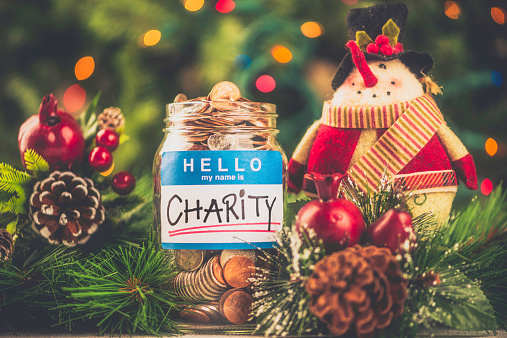 Charity donation jar filled with American currency in holiday setting