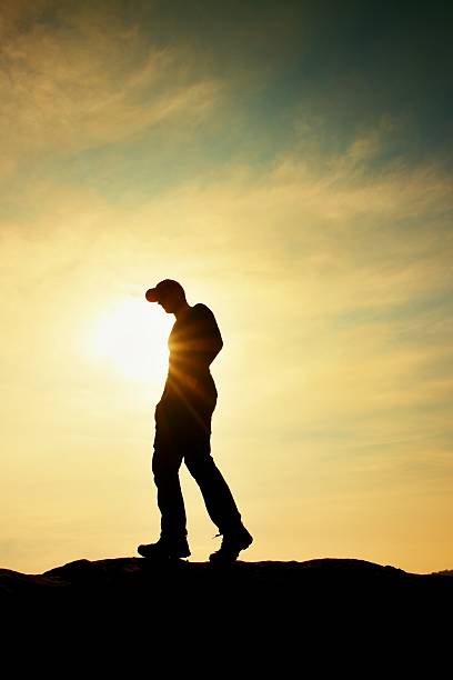 istock Man with cap on rocky peak. Rocky summit at Sun 521622774