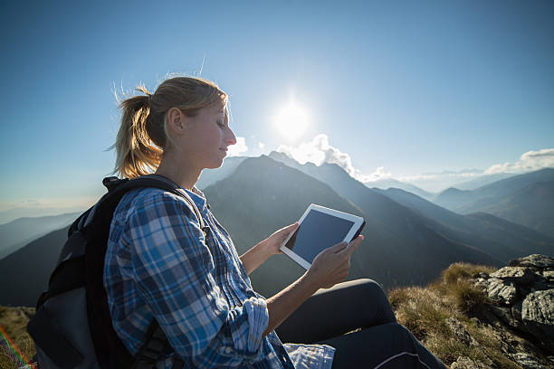 istock Woman at top of mountain using digital tablet 521624243