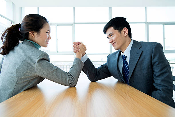 Arm wrestling Side view of businessman and businesswoman arm wrestling on table in the office. business men wrestling women stock pictures, royalty-free photos & images